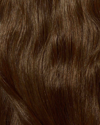 A close-up of dark brown hair featuring bronzed brown hair extensions.