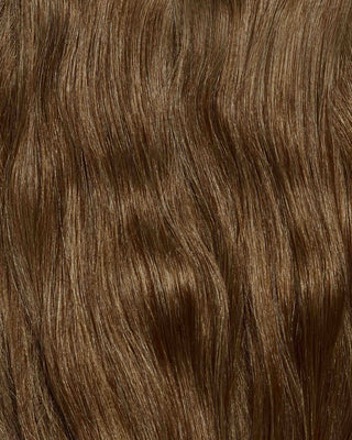 A hair swatch of wavy honey brown hair extensions, showcasing rich color and texture.