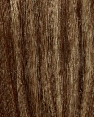 A close-up of long, blonde hair extensions in a honey-browned caramel shade.