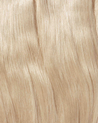 A close-up of a blonde wig featuring long, wavy hair, showcasing the texture and volume of hair extensions.