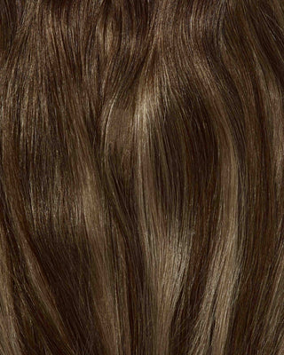 A close-up of hair featuring brown and blonde highlights, showcasing Rooted Caramelt hair extensions.