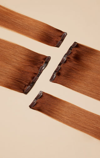Three Brown, Cream, and chocolate clip-in hair extensions in a light pink color background.