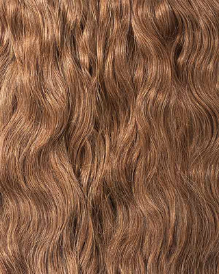 A close-up of long, wavy brown hair showcasing luxurious hair extensions for added volume and length.