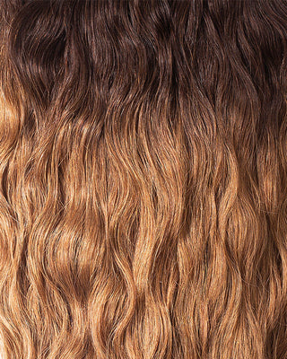 A close-up of long, wavy golden hair extensions, showcasing their luxurious texture and vibrant color.