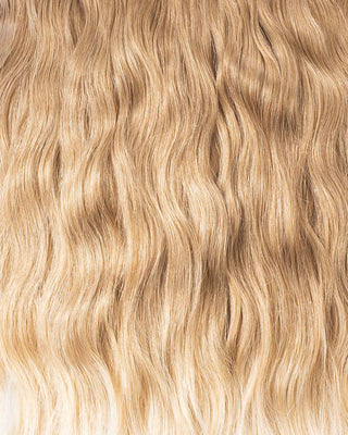 A detailed view of luxurious, long wavy blonde hair extensions, highlighting their softness and movement.