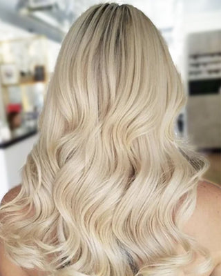 A woman with golden blonde long hair extension waves and curls.