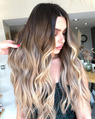 In a hair salon, a woman with Melrose Balayage B3 hair extensions by Glam Seamless, showcasing a woman with long wavy hair