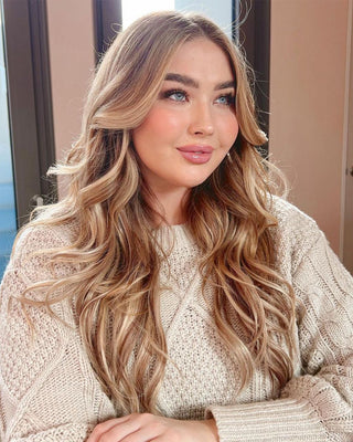 A woman with long wavy hair, enhanced by hair extensions, wearing a cozy sweater, exuding warmth and style.