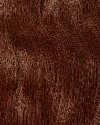 A close-up of vibrant red hair texture, showcasing the intricate details of hair extensions.